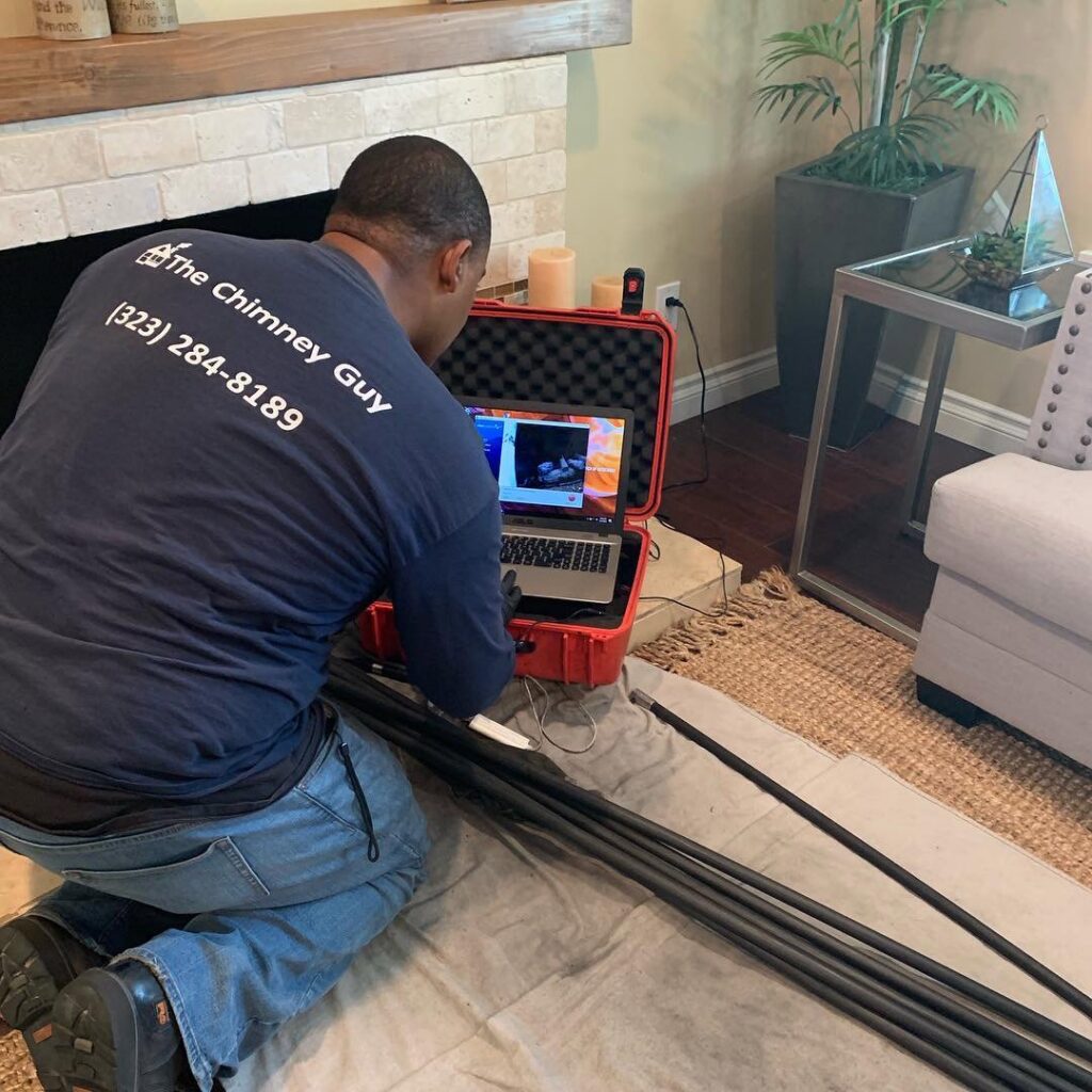 A technician from The Chimney Guy performing a chimney inspection using a camera system and laptop in Los Angeles, CA.
