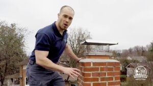 A chimney sweep technician inspecting a chimney on a roof for Rooftop Chimney Sweeps in Alexandria, VA.