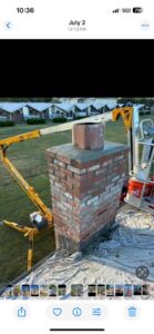 A chimney reconstruction project in progress on a roof, with a lift truck providing access, by Harry's Quality Chimney Services in Kansas City, MO