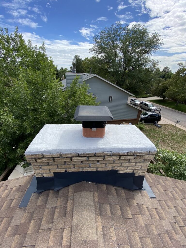 A chimney on a residential roof undergoing repair and maintenance by Top Chimney Fix in Denver, CO.