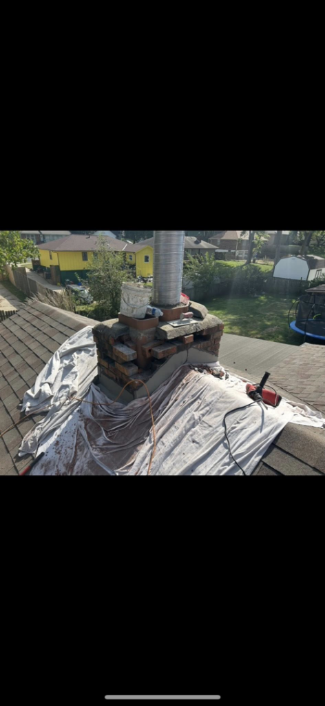A chimney under repair or construction with a flexible metal liner and protective tarps on a roof by Harry's Quality Chimney Services in Kansas City, MO