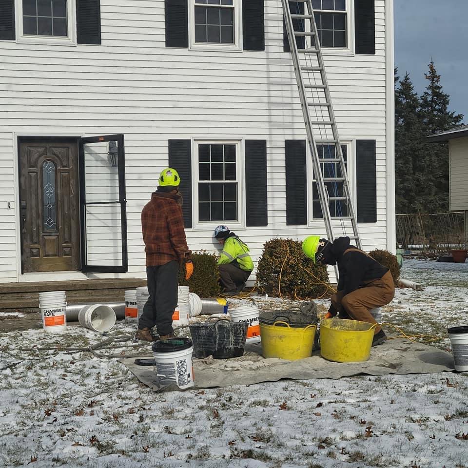 A chimney repair crew working outside a house in winter with equipment and 'Chamber Safe' buckets by Century Chimney Sweep and Repair in Cleveland, OH