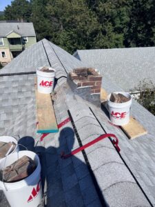 Chimney repair or demolition work in progress on a roof with buckets of debris by Granite State Chimney in Manchester, NH
