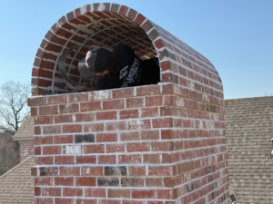 Technicians performing chimney repair or installation work on a brick chimney for NEA Chimney Services in Paragould, AR