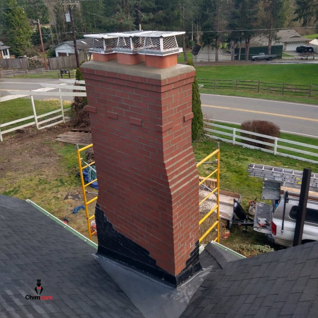A tall brick chimney undergoing repair or construction with scaffolding visible, handled by Chimney Care experts in Doraville, GA.