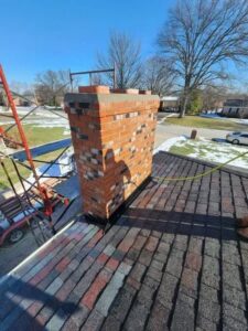 A brick chimney on a residential roof with scaffolding, indicating repair work in progress by The Chimney Doctor in Louisville, KY.