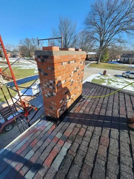 A brick chimney on a residential roof with scaffolding, indicating repair work in progress by The Chimney Doctor in Louisville, KY.