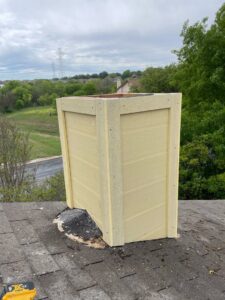 Chimney repair in progress with yellow siding being installed on a roof by The Texan Chimney Sweep San Antonio, TX.