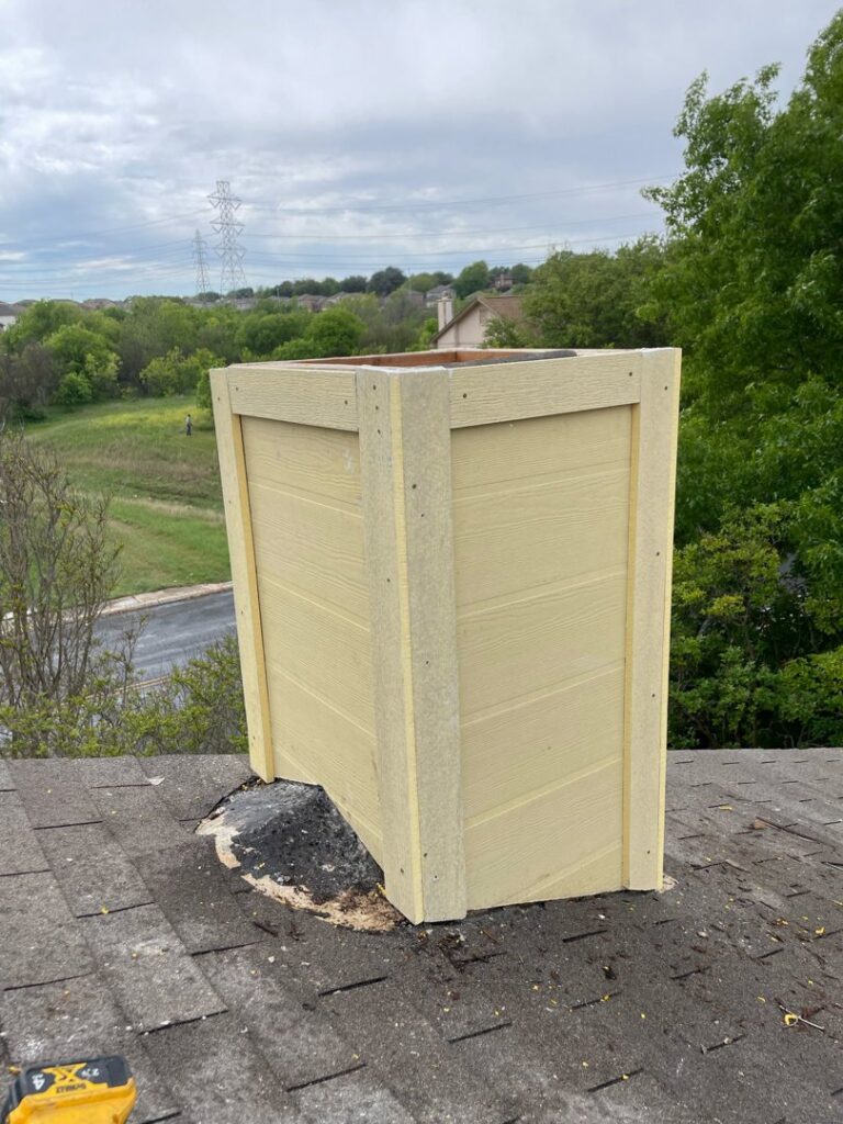 Chimney repair in progress with yellow siding being installed on a roof by The Texan Chimney Sweep San Antonio, TX.
