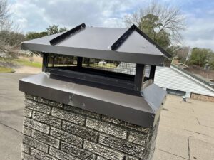 Two Brushers Chimneys workers on a roof, one on a ladder performing chimney repair in Houston, TX.