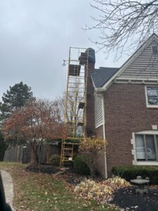 Scaffolding set up next to a brick chimney on a residential home, indicating chimney maintenance or repair by Indy Ignited in Indianapolis, IN.