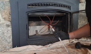 A chimney sweep cleaning a fireplace insert with a rotary brush at Western Expanse Chimney and Hearth in De Smet, ID.
