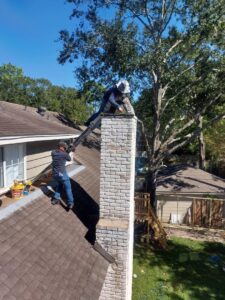 A chimney sweep from Brushers Chimneys cleaning the chimney flue with a brush from the rooftop in Houston, TX.