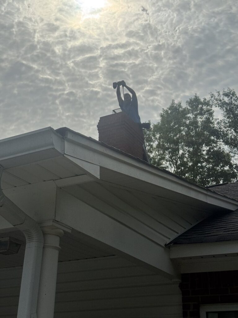 A Soot Masters Chimney Service LLC professional performing a chimney sweep from the rooftop in Jackson, MS.