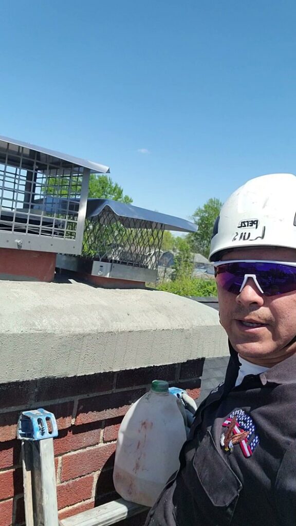 A chimney technician from Eagles Nest Chimney Services and more of Cincinnati LLC on a roof, with chimney caps visible in the background in Cincinnati, OH.