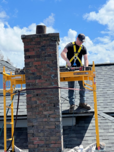 A chimney technician on scaffolding servicing a brick chimney for Western Expanse Chimney and Hearth in De Smet, ID.