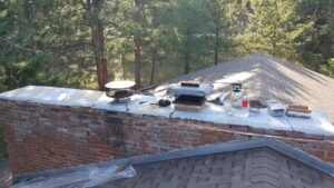 A chimney top with various tools and equipment laid out, indicating a chimney sweep job by Chimney Karma in Fort Collins, CO.