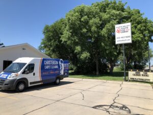 A Christenson Carpet Cleaning & Restoration service van parked outside a commercial building in Hastings, NE.