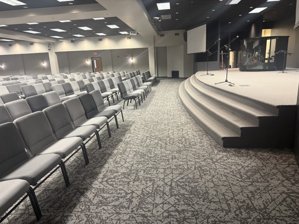 New carpet installed in a large church auditorium with seating and a stage by Rayman Flooring in Aberdeen, SD