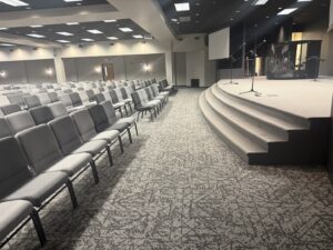 New carpet installed in a large church auditorium with seating and a stage by Rayman Flooring in Aberdeen, SD