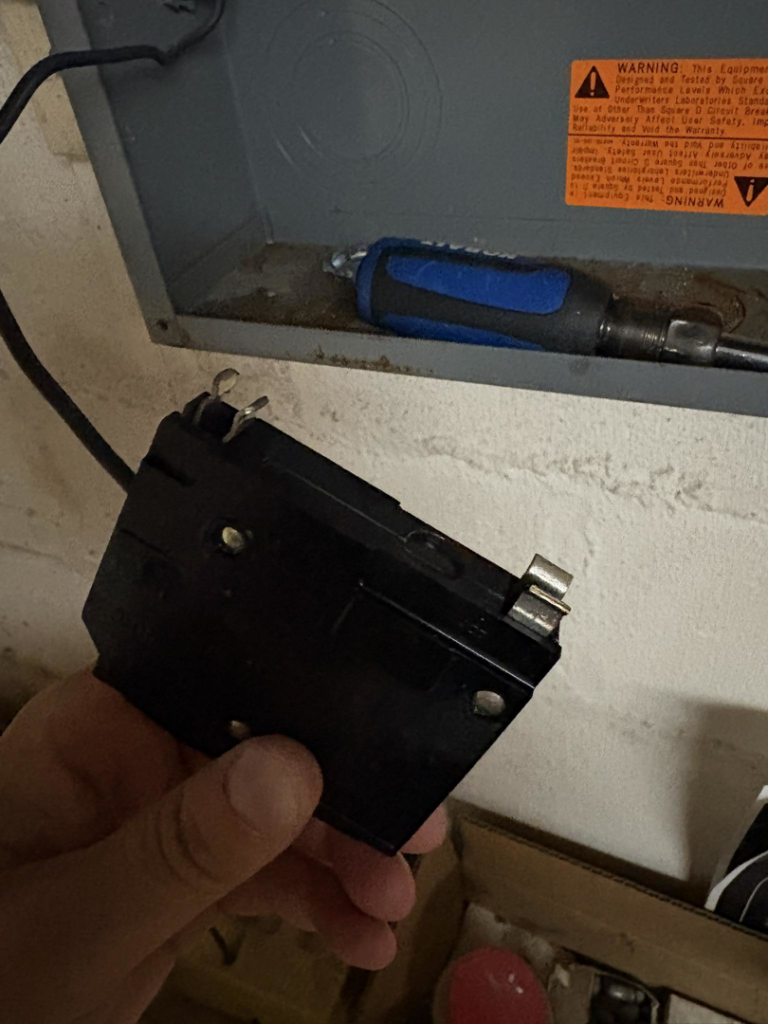A hand holding a circuit breaker, ready for replacement or installation by SandD electric in Winchester, VA.