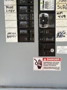 Close-up of circuit breakers in an electrical panel with a danger warning, handled by Esmeralized Electric in San Jose, CA.