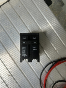 Two 60-amp circuit breakers resting on a metallic workbench, ready for electrical installation by MLEC in Annapolis, MD