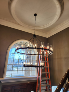 A circular chandelier installed in a high-ceiling room by Ed's Electrical & Mounting services in Chicago, IL.