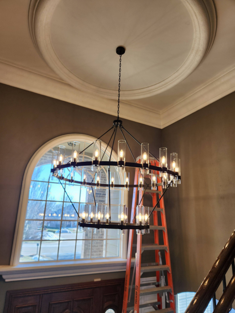 A circular chandelier installed in a high-ceiling room by Ed's Electrical & Mounting services in Chicago, IL.