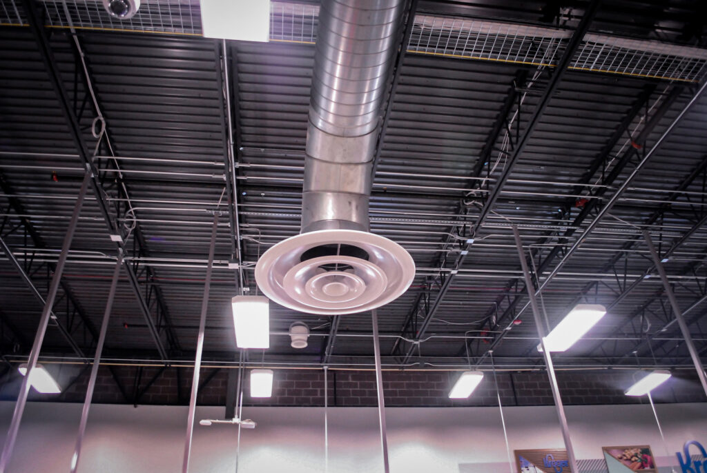 A circular HVAC diffuser and exposed ductwork in a commercial ceiling, installed by Air-Flow Mechanical Services, Inc. in Cincinnati, OH.