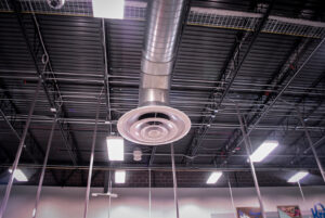 A circular HVAC diffuser and exposed ductwork in a commercial ceiling, installed by Air-Flow Mechanical Services, Inc. in Cincinnati, OH.