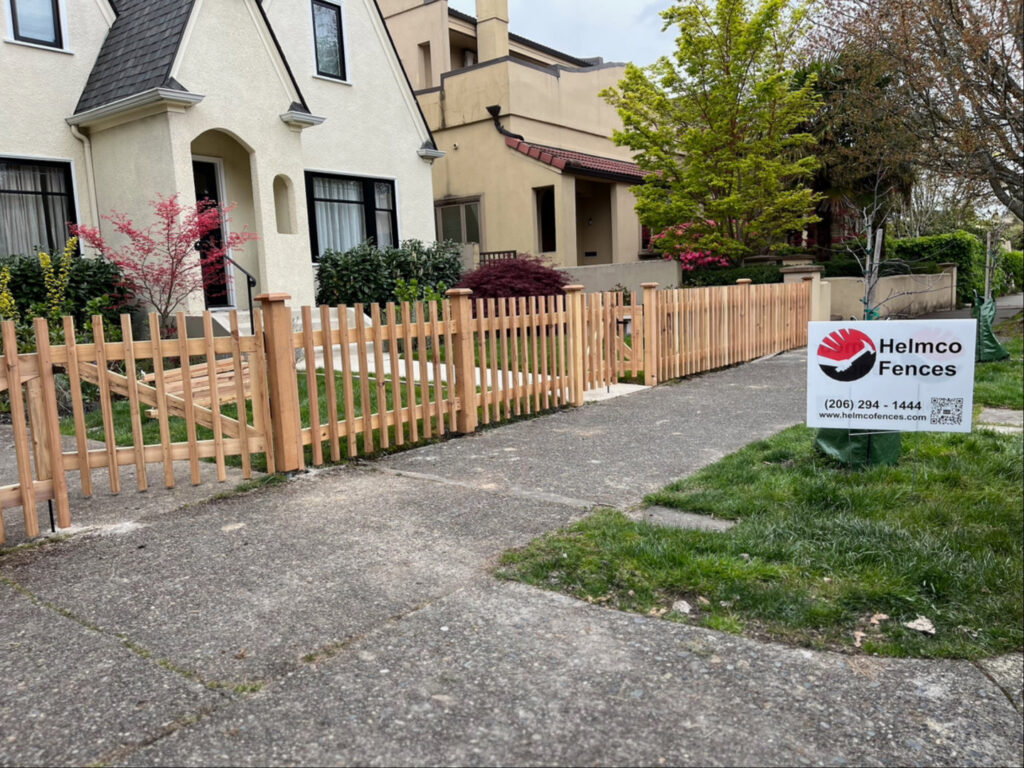 A classic wooden picket fence installed along a sidewalk by Helmco Fences in Seattle, WA.
