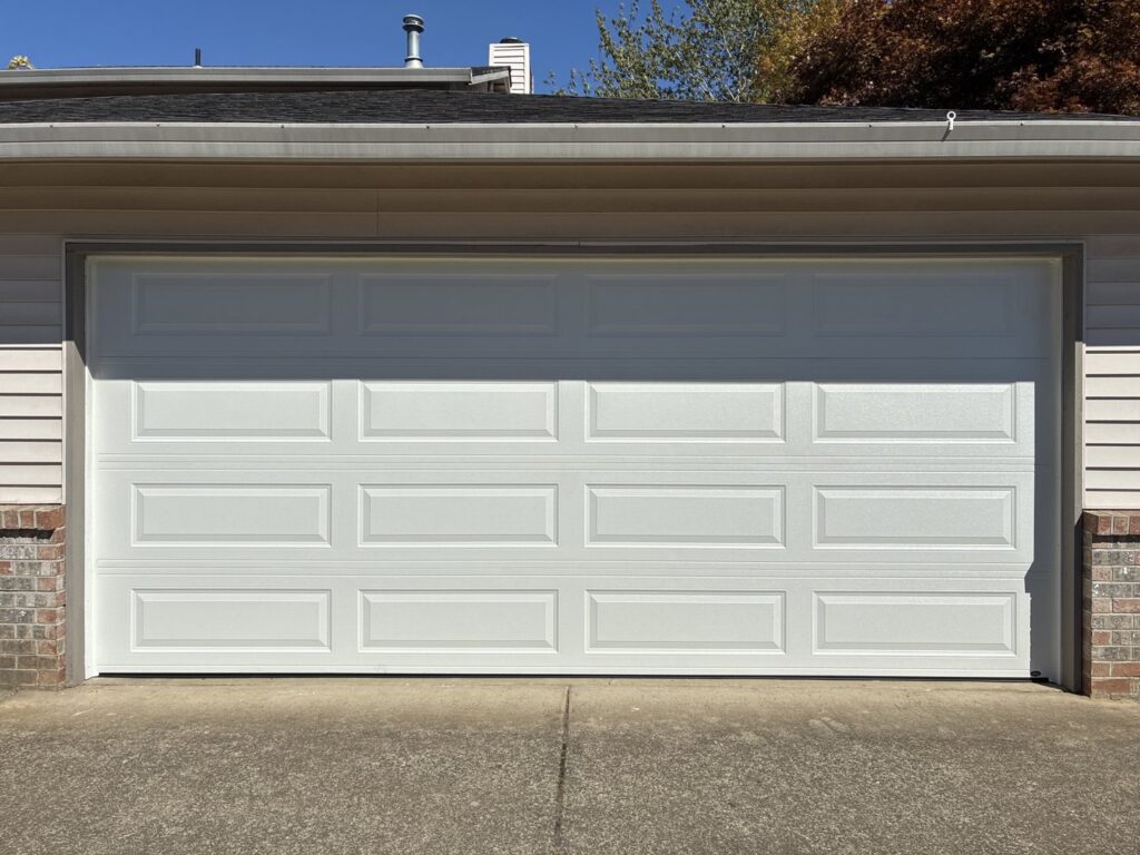 A classic white paneled garage door on a residential home, installed by Coast To Coast Garage Door LLC in Vancouver, WA.