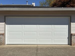 A classic white paneled garage door on a residential home, installed by Coast To Coast Garage Door LLC in Vancouver, WA.