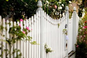 A beautiful classic white picket fence adorned with flowers, maintained by Walt's Fence Staining in Allen, TX.