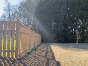 A classic wood picket fence installed along a residential property line, showcasing work by Holmes Fence Company in Chattanooga, TN.