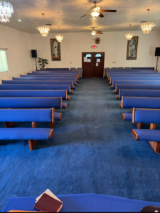 A large room with a freshly cleaned blue carpet and pews by Mystic Steam Carpet & Upholstery Cleaning in Long Beach, CA