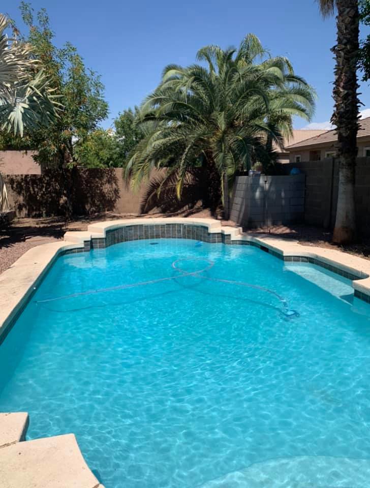 A clean, blue pool with a pool hose visible, indicating ongoing maintenance by Space Ranger Pools in Gilbert, AZ.