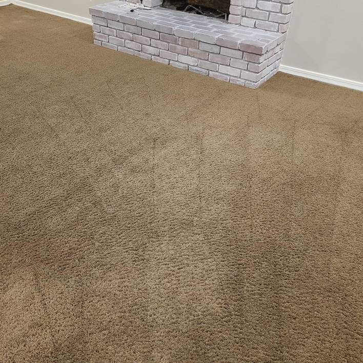 A clean brown carpet with visible grooming lines next to a fireplace, serviced by Epic Carpet and Tile Care in Phoenix, AZ
