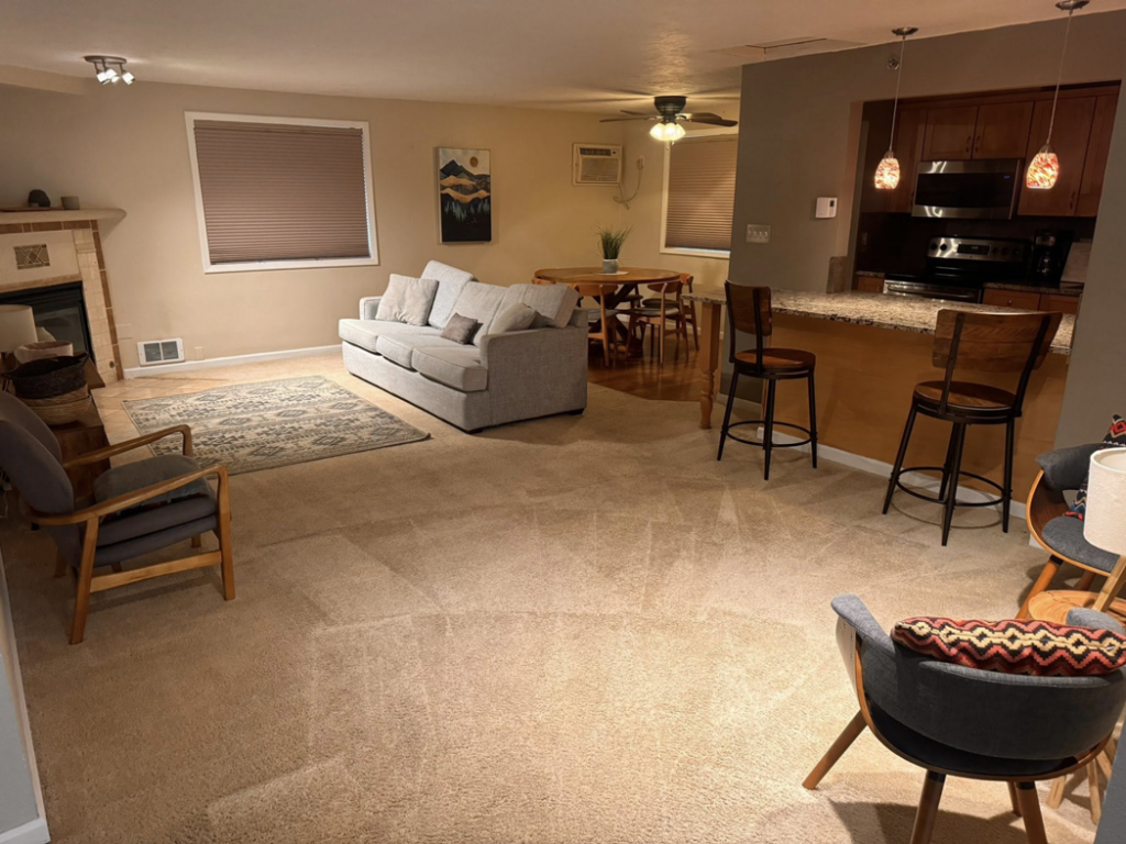 A clean, carpeted living room and dining area, showcasing the work of C & C Carpet Cleaning in Spokane, WA.