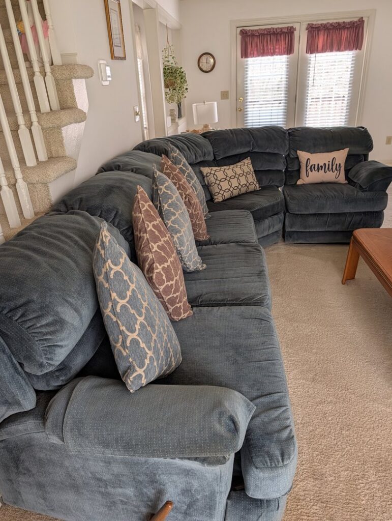 A freshly cleaned carpeted living room with a large sectional sofa by Greensboro Carpet Cleaning - DeepClean in Greensboro, NC