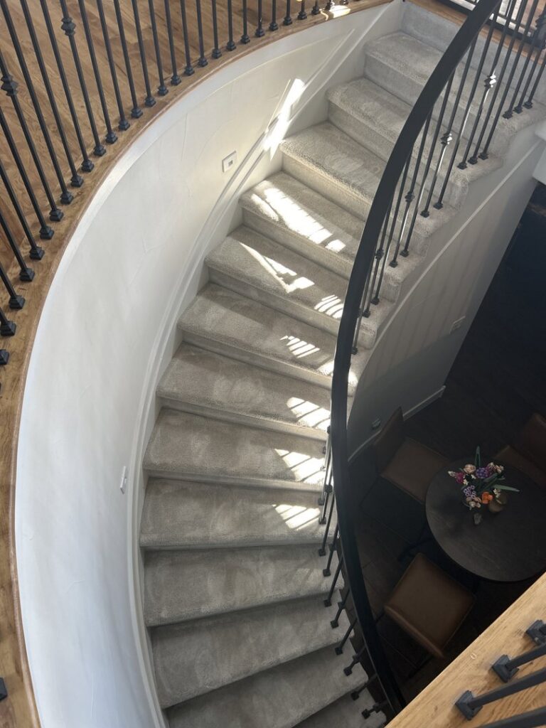A clean, light-colored carpeted spiral staircase after professional cleaning by STC Carpet Care in Arvada, CO