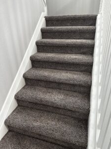 A clean, dark grey speckled carpeted staircase after professional service by STC Carpet Care in Arvada, CO