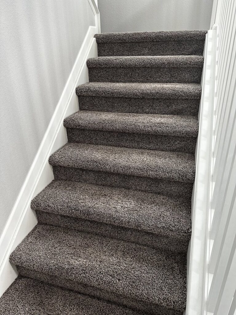 A clean, dark grey speckled carpeted staircase after professional service by STC Carpet Care in Arvada, CO