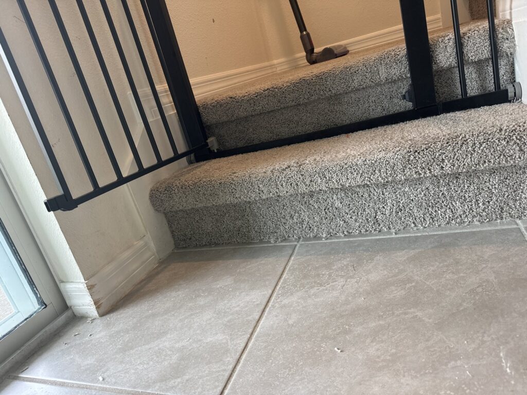 A clean, well-maintained carpeted staircase leading to a tiled floor, showcasing quality work by Mr. Carpet Cleaning Orlando, FL.