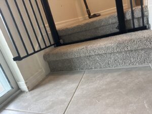 A clean, well-maintained carpeted staircase leading to a tiled floor, showcasing quality work by Mr. Carpet Cleaning Orlando, FL.