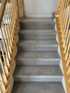 A set of clean, carpeted stairs with light wooden railings, showcasing professional carpet cleaning by Reno Kwik Dry Total Cleaning in Sparks, NV.