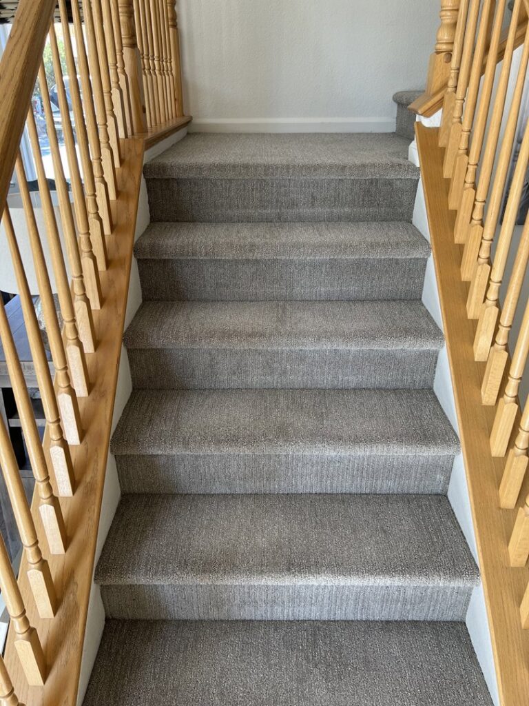 A set of clean, carpeted stairs with light wooden railings, showcasing professional carpet cleaning by Reno Kwik Dry Total Cleaning in Sparks, NV.