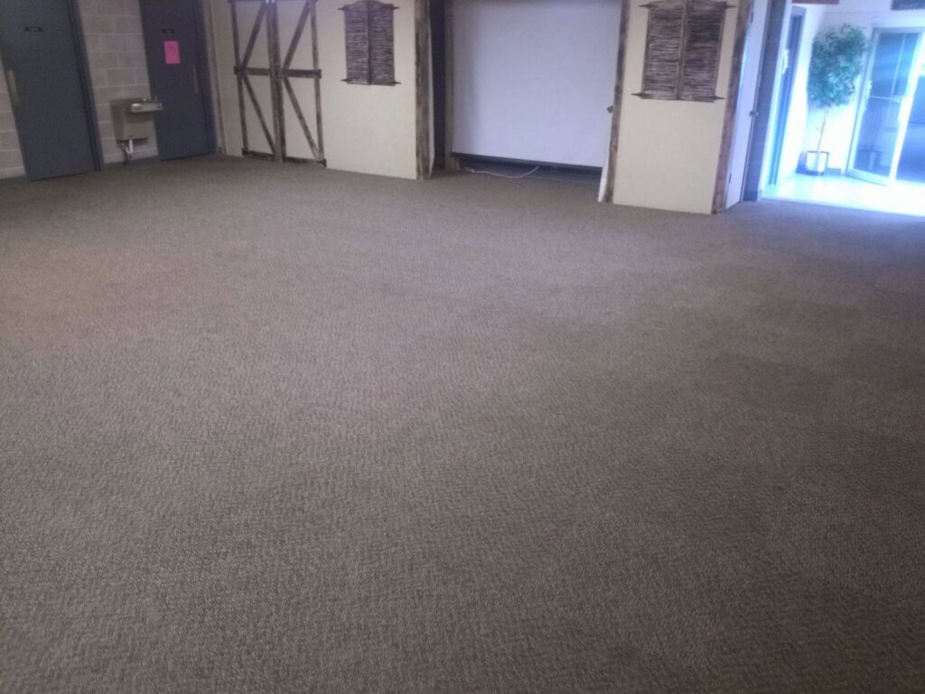 A large room with a clean, dark gray commercial carpet, expertly installed or cleaned by Real Green Cleaning in Indianapolis, IN.