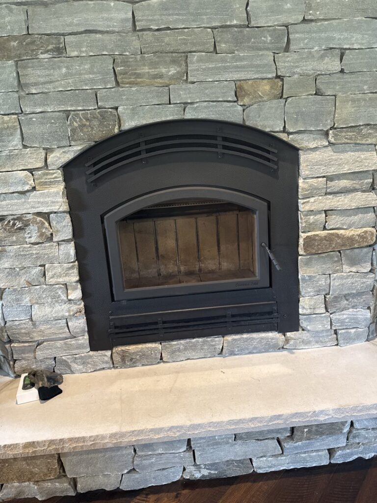 The clean interior of a fireplace firebox with a metal grate, maintained by Chimney Mechanix of Indiana in Lafayette, IN.